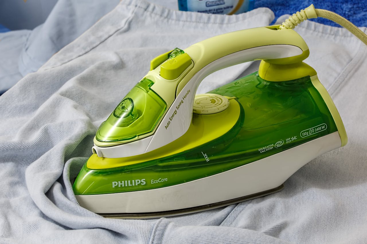 portfolio-02 Green Philips EcoCare iron on a wrinkled shirt, ready for ironing.