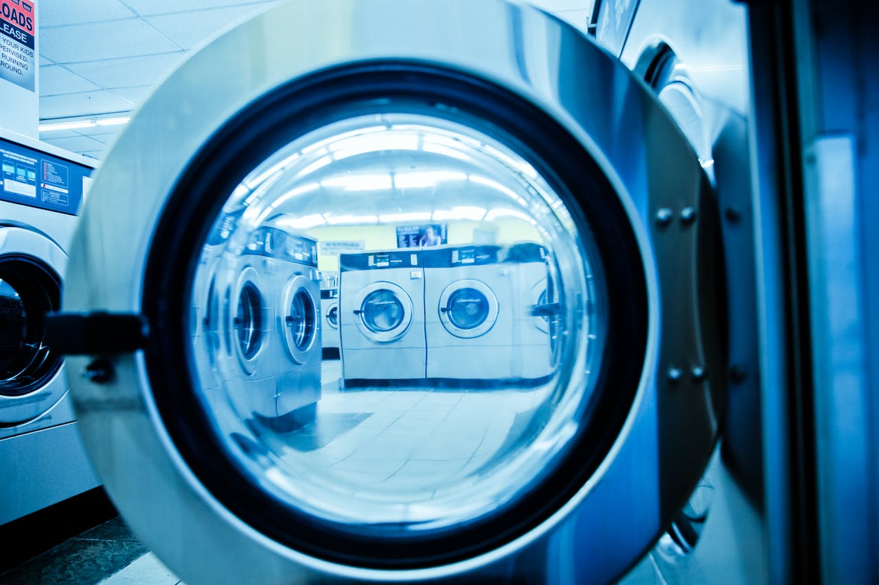 stats-img Interior view of a modern laundromat with rows of steel washing machines.